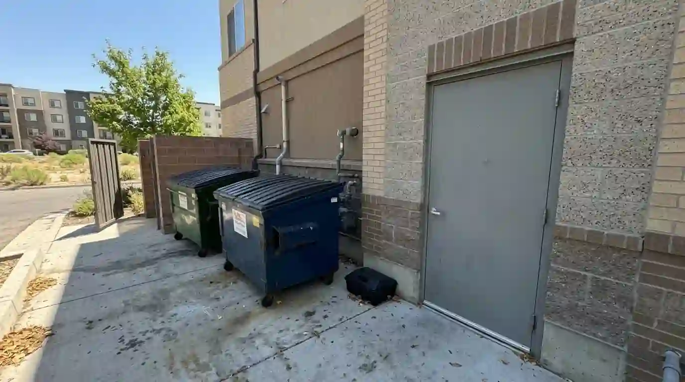 Apartment trash room with lidded bins and a rodent station
